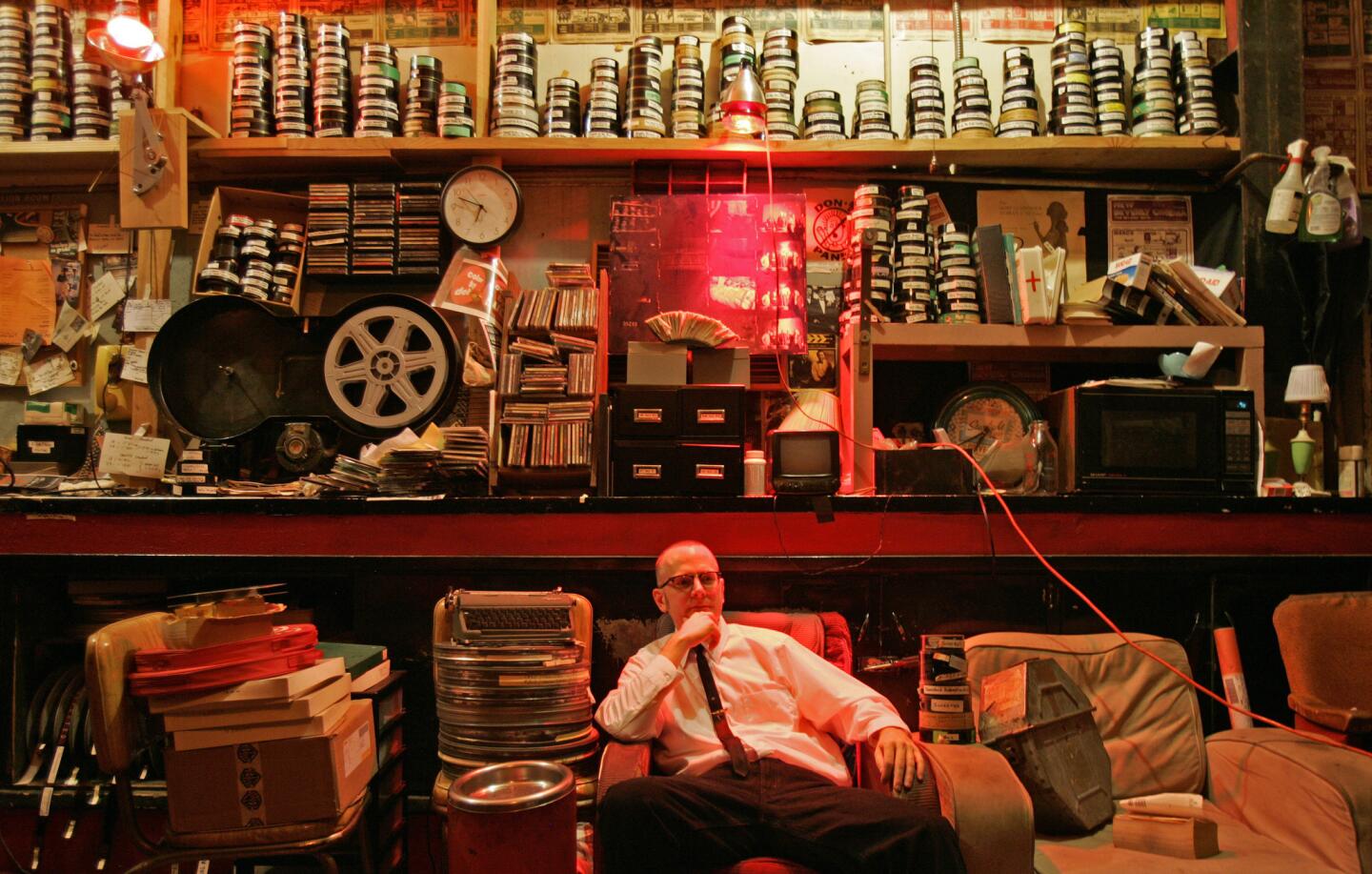 Brian Quinn, a manager at the New Beverly, sits in the movie house's projection room surrounded by o