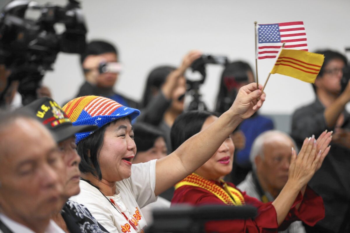 Victoria Kim waves the flags of the U.S. and the former South Vietnam during a town hall meeting with the U.S. ambassador to Vietnam, Ted Osius, at Coastline Community College in Little Saigon.