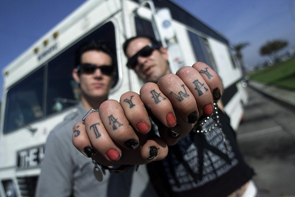 The Hunns guitarist Rob Milucky, left, and Duane Peters pose in front of their touring RV in Newport Beach.