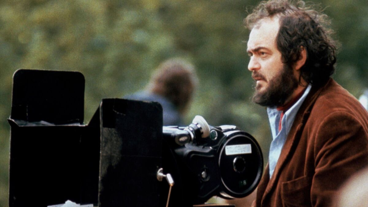 man in brown corduroy jacket behind a camera