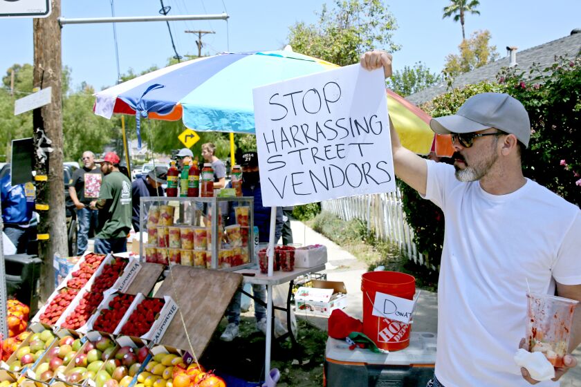 Kelly Parra, 50 of Woodland Hills, shows his support for street fruit vendor Tomas Escamilla at the corner of Canoga Ave. and Dumetz Road, in Woodland Hills on Saturday, May 7, 2022. A rally was held today in support of Escamilla after he was recently attacked by a local neighbor who destroyed his fruit cart.