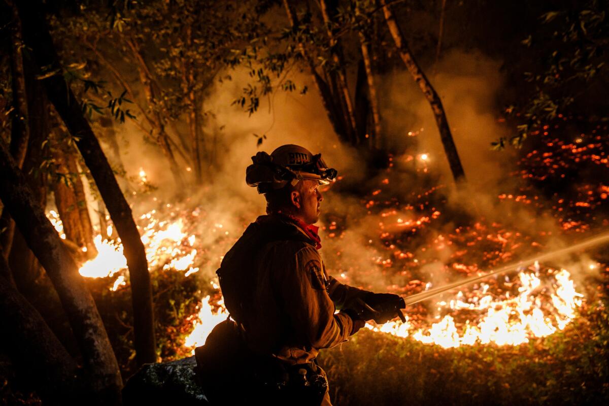 Firefighter Mario Topete attacks flames as his unit tries to prevent a fire from crossing Highway 29 north of Calistoga on Oct. 12.