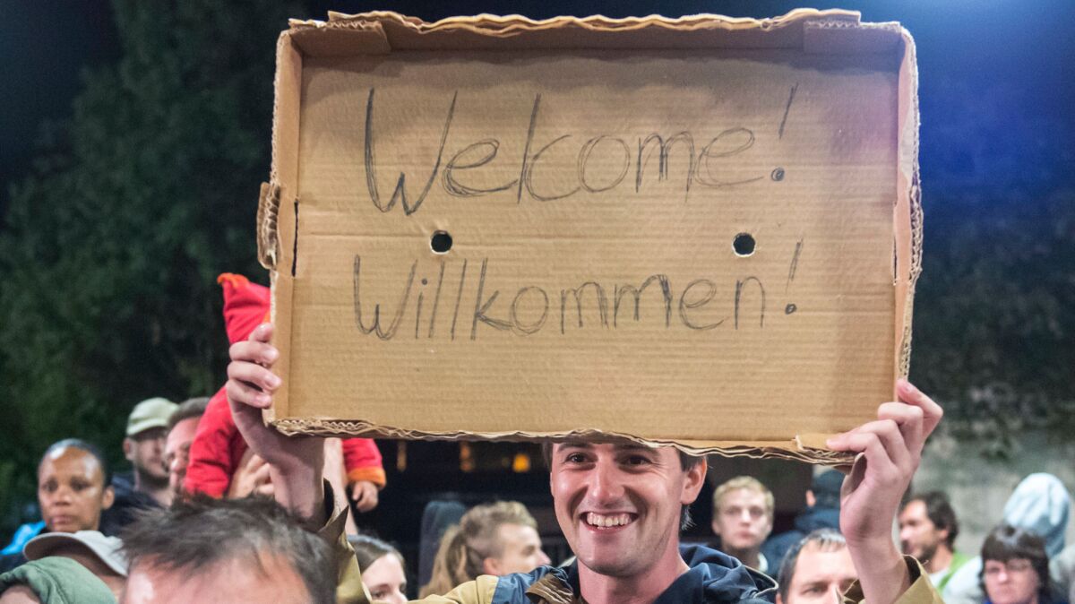 In this Sept. 5, 2015, picture, a man holds a sign welcoming arriving refugees at the train station in Saalfeld, central Germany.