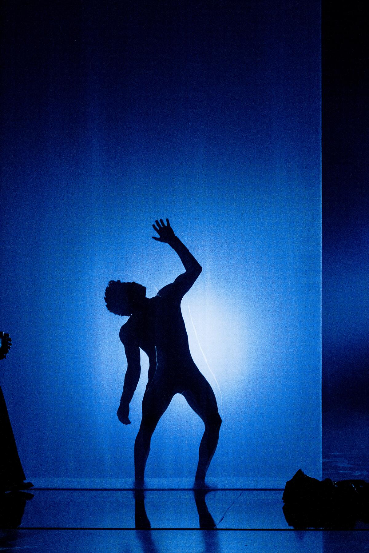 A man reaching up, creating a shadow with blue light around him