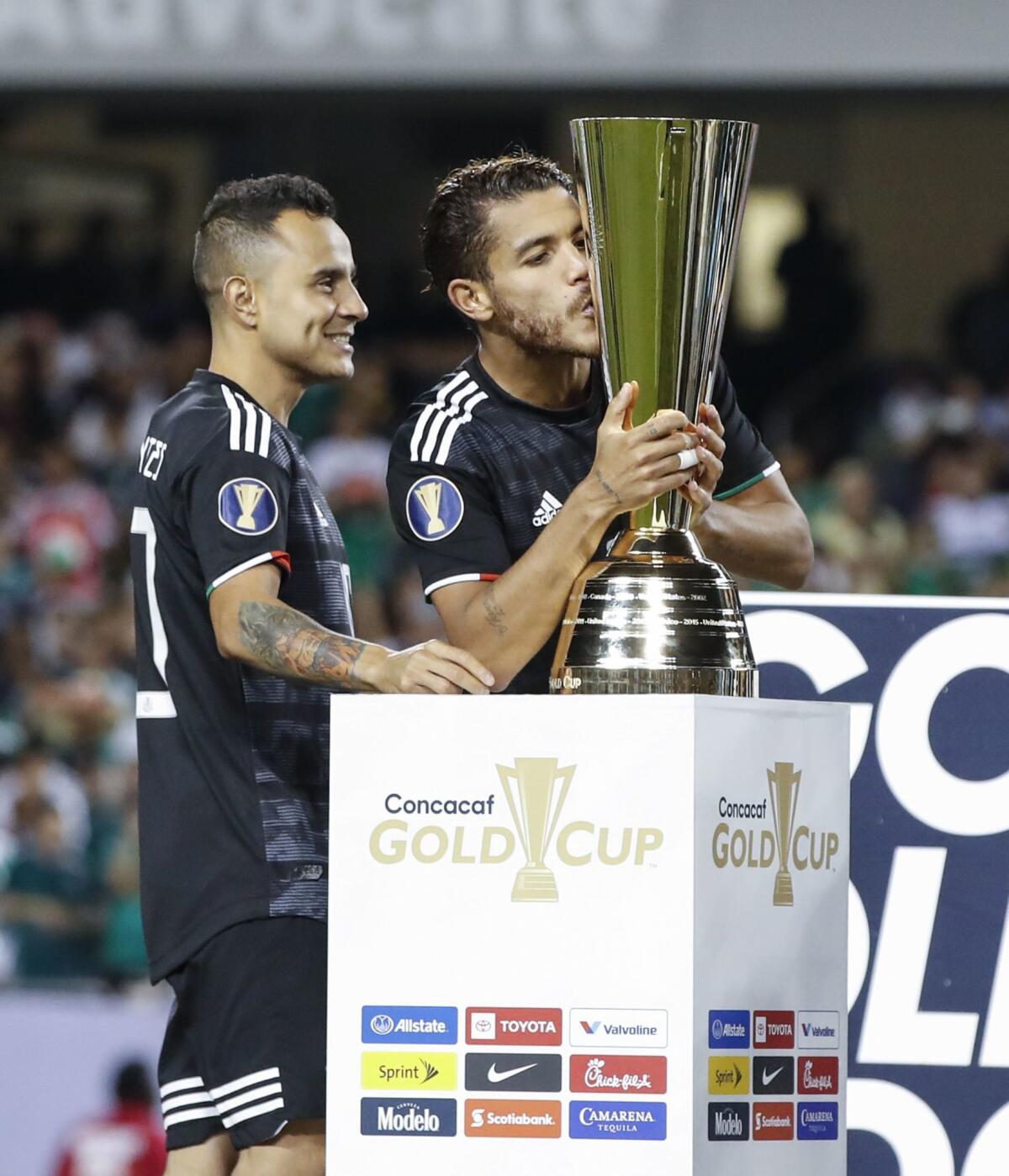 Mexico midfielder Jonathan Dos Santos (R) kisses the Gold Cup after beating the US during the 2019 Concacaf Gold Cup final football match between USA and Mexico on July 7, 2019 at Soldier Field stadium in Chicago, Illinois. - Mexico defeated the US 1-0.