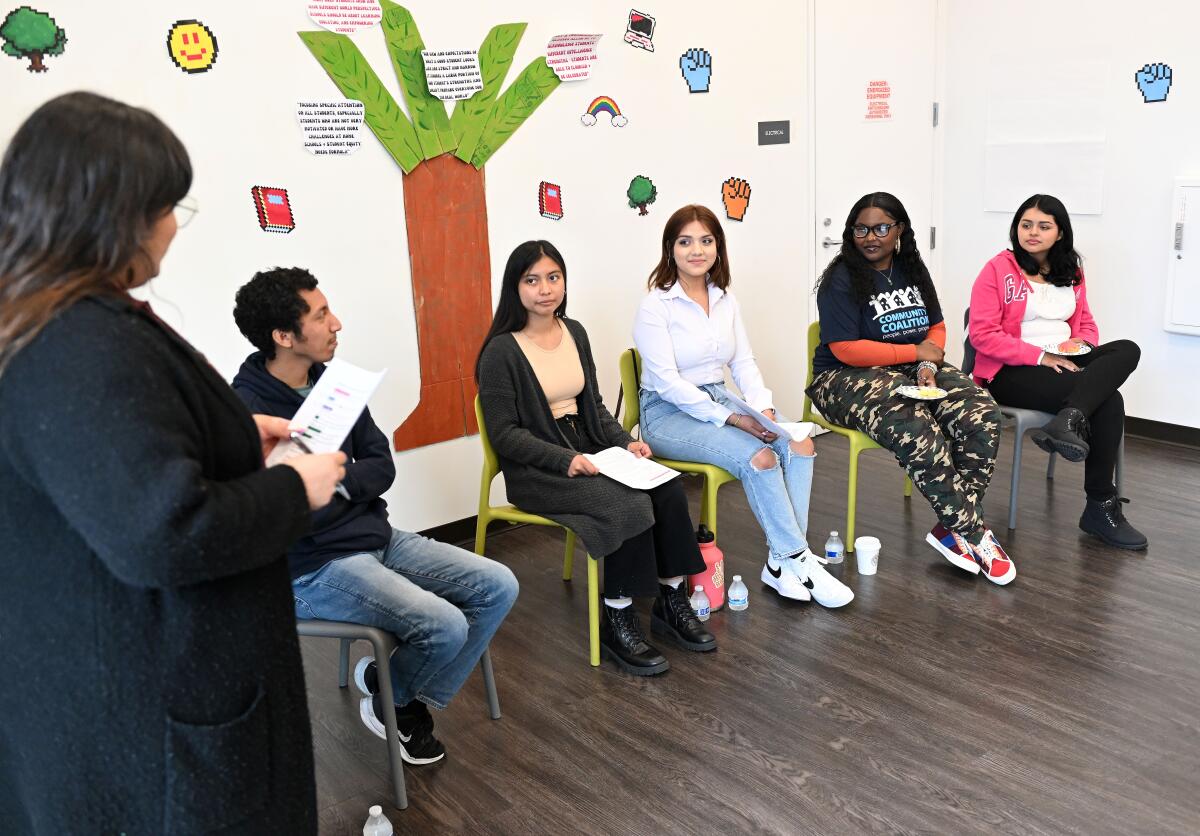 Five graduating seniors sit in a semi-circle to speak. 