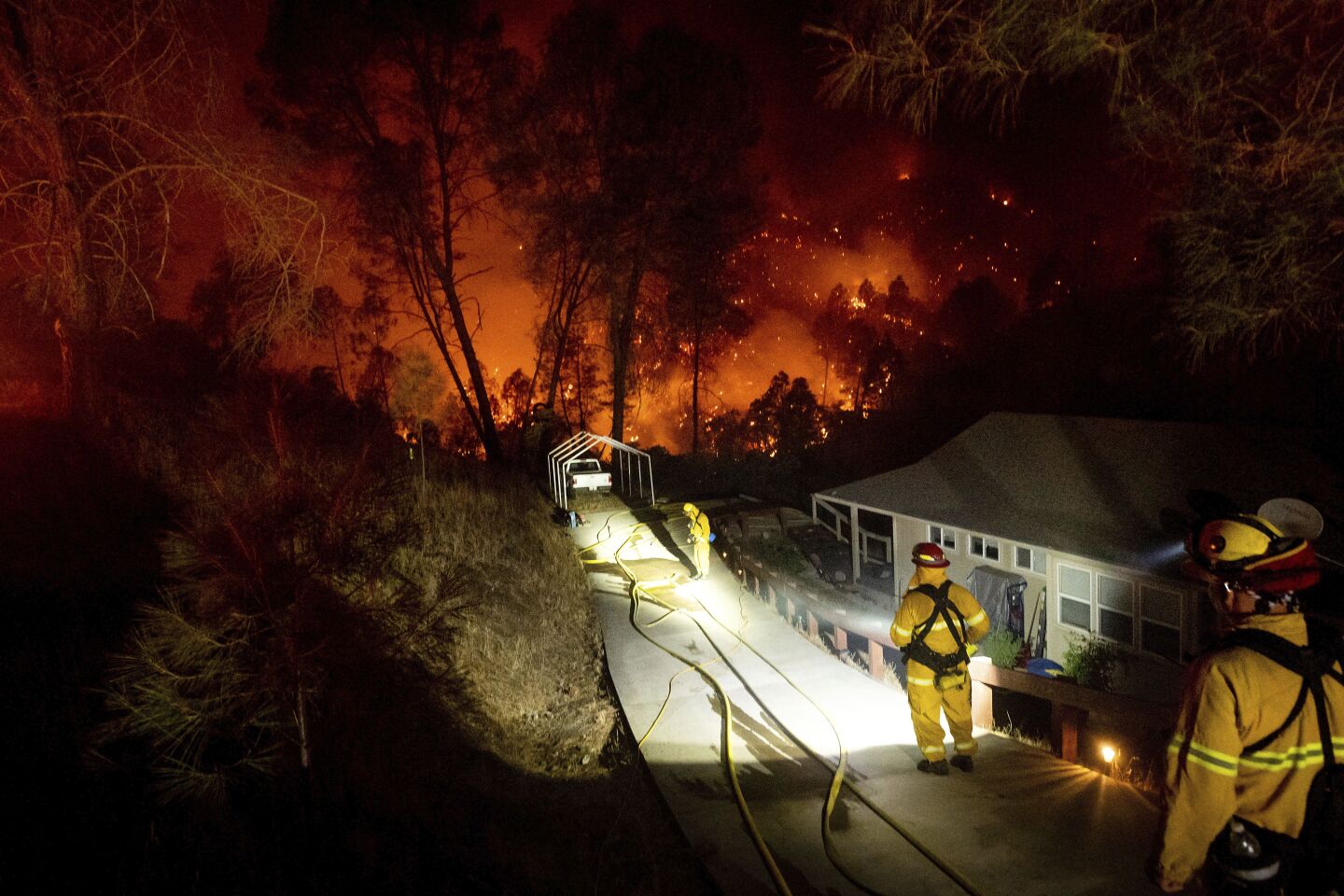 Firefighters protect a home in the Berryessa Estates neighborhood of unincorporated Napa County, Calif., as the LNU Lightning Complex fires burn on Friday. The blaze forced thousands to flee and destroyed hundreds of homes and other structures.