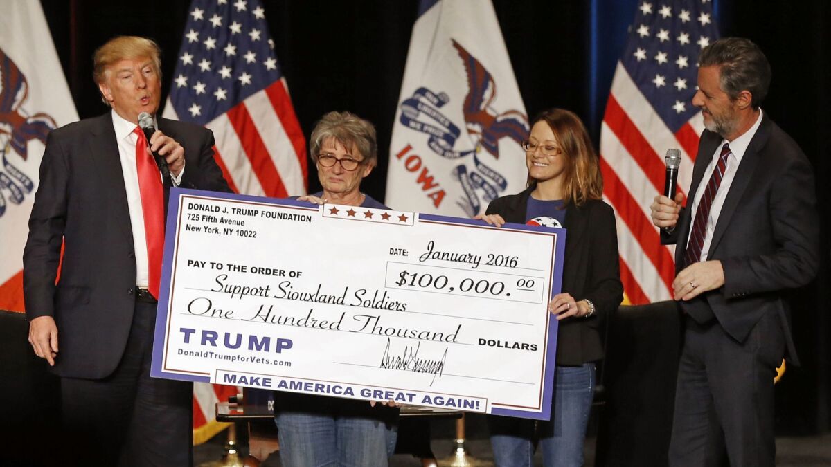 During a January 2016 campaign event, Donald Trump presents a check from his foundation to members of Support Siouxland Soldiers in Sioux City, Iowa.