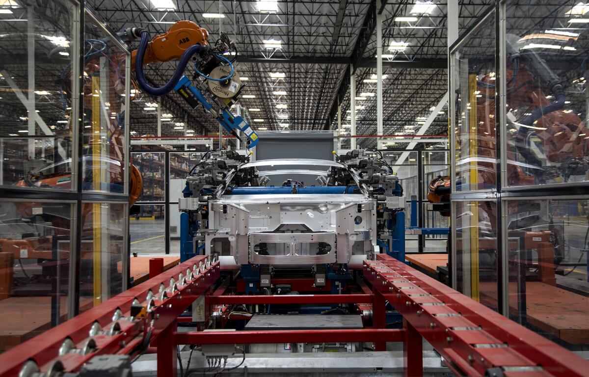 Robots rivet the side frame assembly on the body of a Revero electric car at the Karma automotive factory in Moreno Valley. Karma is the first car-building company in Southern California in decades.