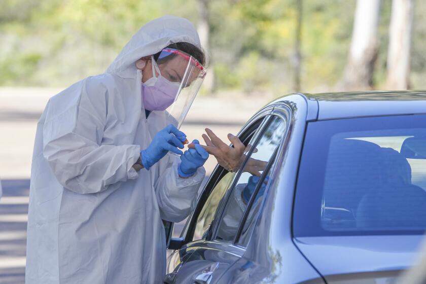 At a drive up testing site, Covid Clinic medical assistant Jennifer Quinlan collects a sample for Coronavirus COVID-19 testing at the San Elijo campus of Mira Costa College on April 15, 2020 in Cardiff, California.