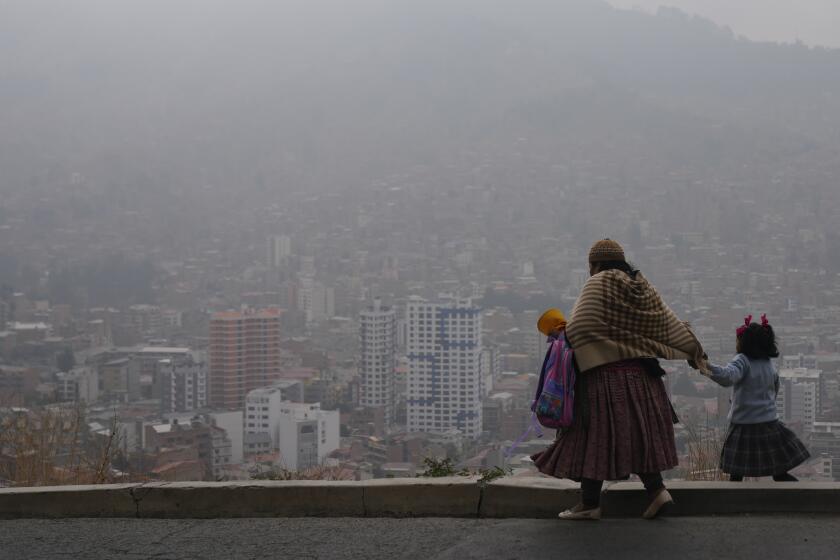 Una mujer acompaña a su hija a la escuela en medio del humo de los incendios forestales en La Paz, Bolivia, el lunes 9 de septiembre de 2024. (AP Foto/Juan Karita)