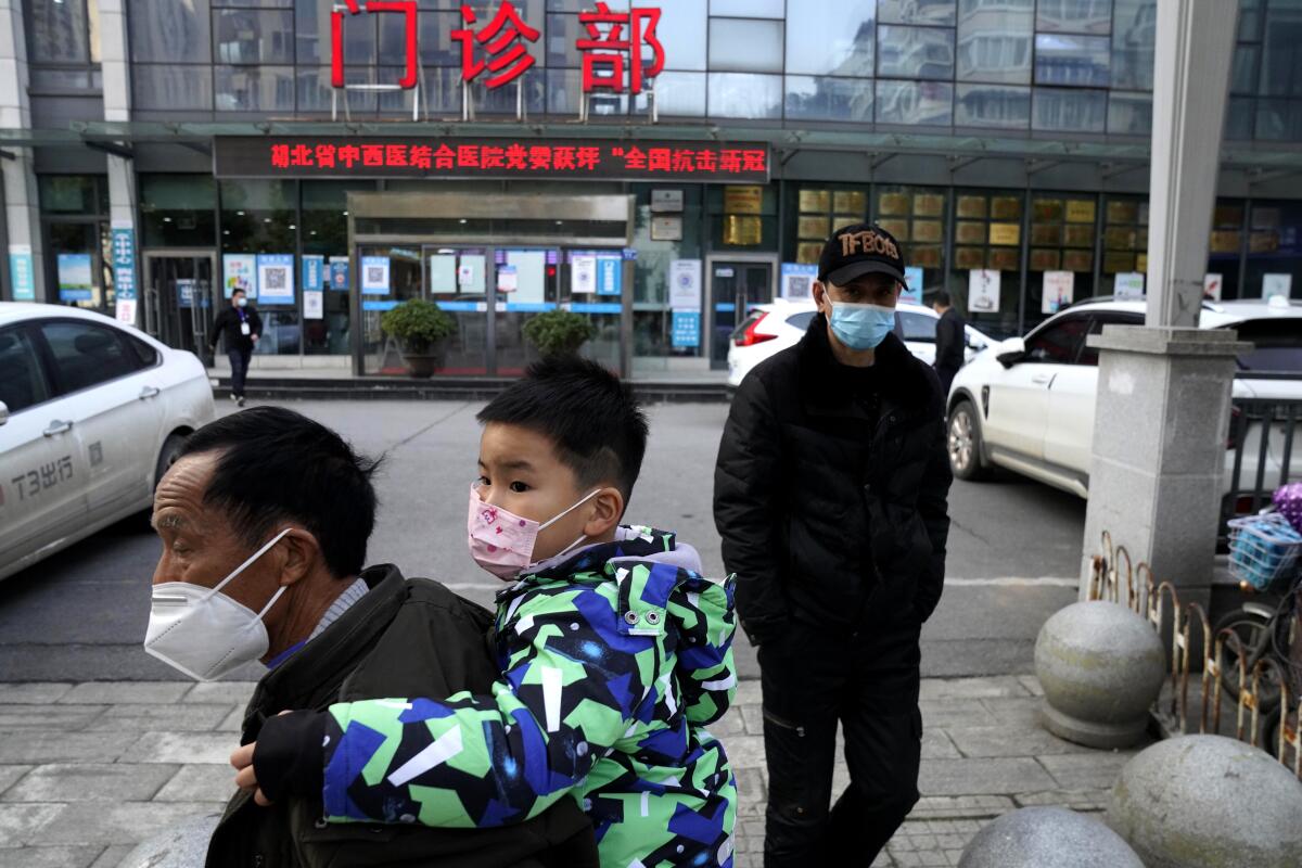 A man carries a child past the clinic of the Hubei Provincial Hospital of Integrated Chinese and Western Medicine.