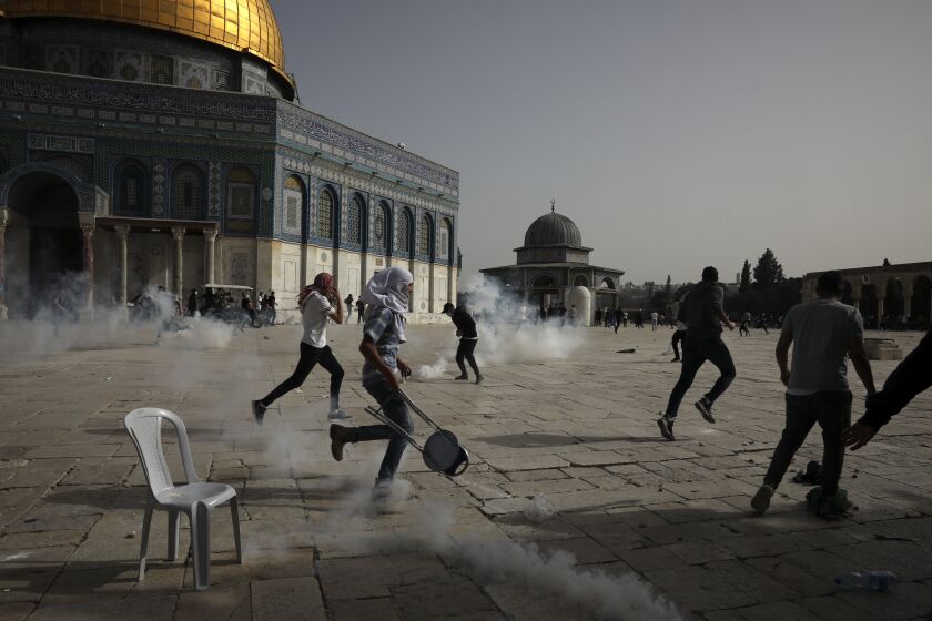 Palestinians run away from tear gas during clashes with Israeli security forces at the Al Aqsa Mosque compound in Jerusalem's Old City Monday, May 10, 2021. Israeli police clashed with Palestinian protesters at a flashpoint Jerusalem holy site on Monday, the latest in a series of confrontations that is pushing the contested city to the brink of eruption. Palestinian medics said at least 180 Palestinians were hurt in the violence at the Al-Aqsa Mosque compound, including 80 who were hospitalized. (AP Photo/Mahmoud Illean)