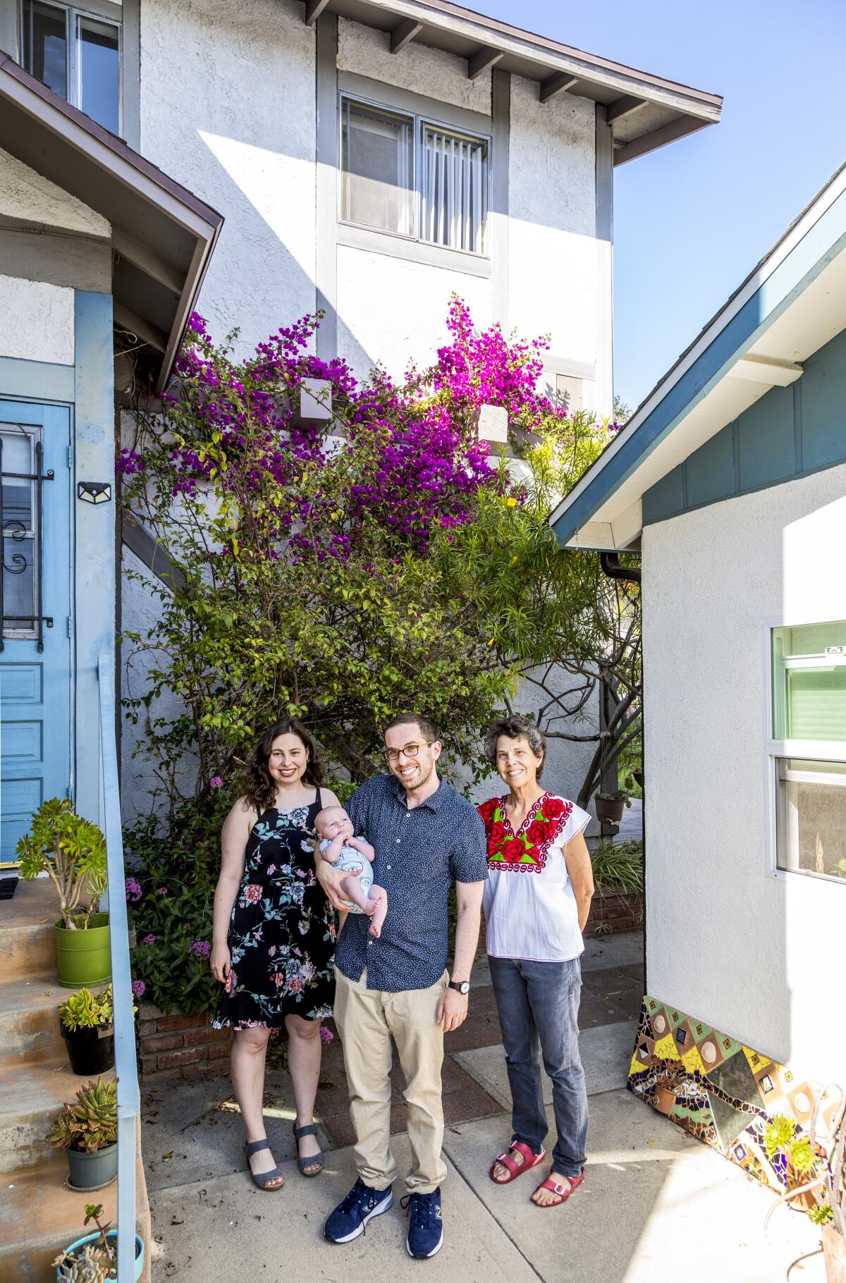  A family of four stands in between two homes 