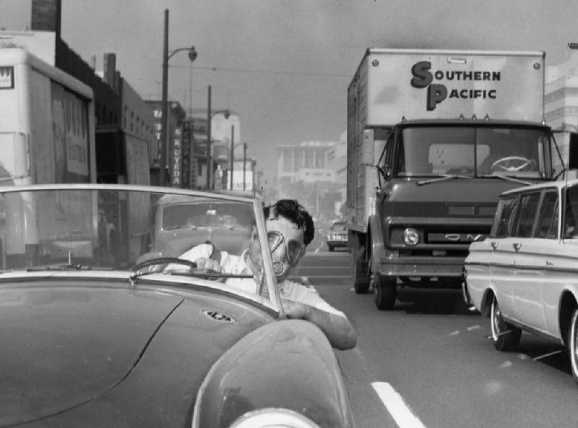 A Los Angeles commuter leans out of his car wearing a gas mask on Oct. 2, 1966. 