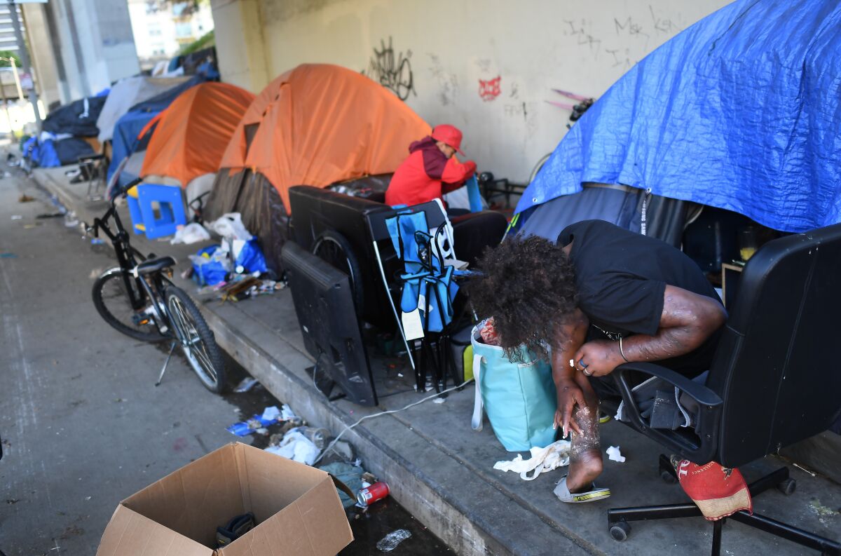 Tracy, a homeless man, applies medicine to his leg along Figueroa Street under the 101 Freeway in downtown Los Angeles on Tuesday.