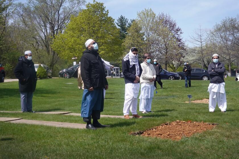 ELGIN, ILLINOIS - MAY 04: Mourners pray at the grave of Ghulam Farid following his burial in Bluff City Cemetery and an earlier funeral service at Masjid Al Huda (also know as the Midwest Islamic Center) on May 04, 2020 in Elgin, Illinois. According to funeral director Rezwan Haque, funerals held at Masjid Al Huda typically draw 150 to 500 mourners but, because of the COVID-19 pandemic, families are informed that they are only allowed 10. Farid's death was not attributed to COVID-19. (Photo by Scott Olson/Getty Images)