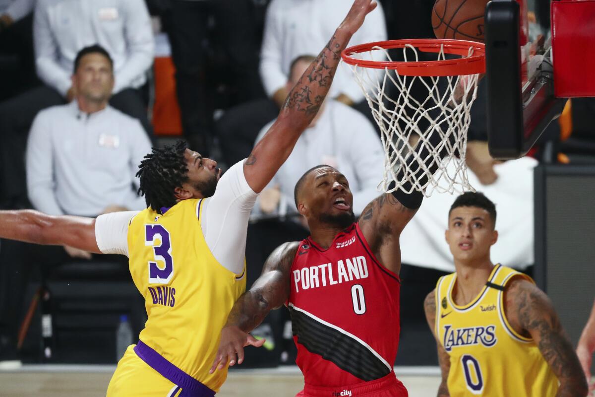 Lakers forward Anthony Davis blocks a shot by Trail Blazers guard Damian Lillard.