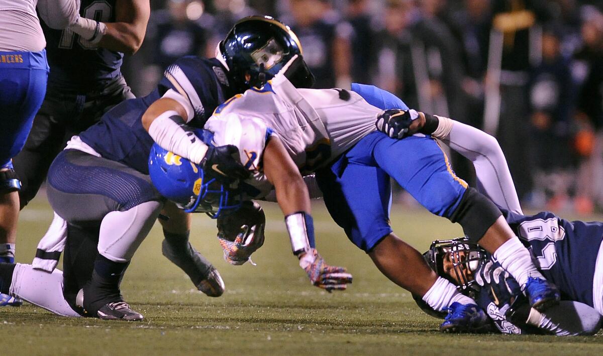 St. John Bosco’s Clive Manuao, left, and Nahe Sulunga, right, take down Bishop Amat’s Torreahno Sweet, center, during the Pac-5 Division football semifinal at Cerritos College on Friday.