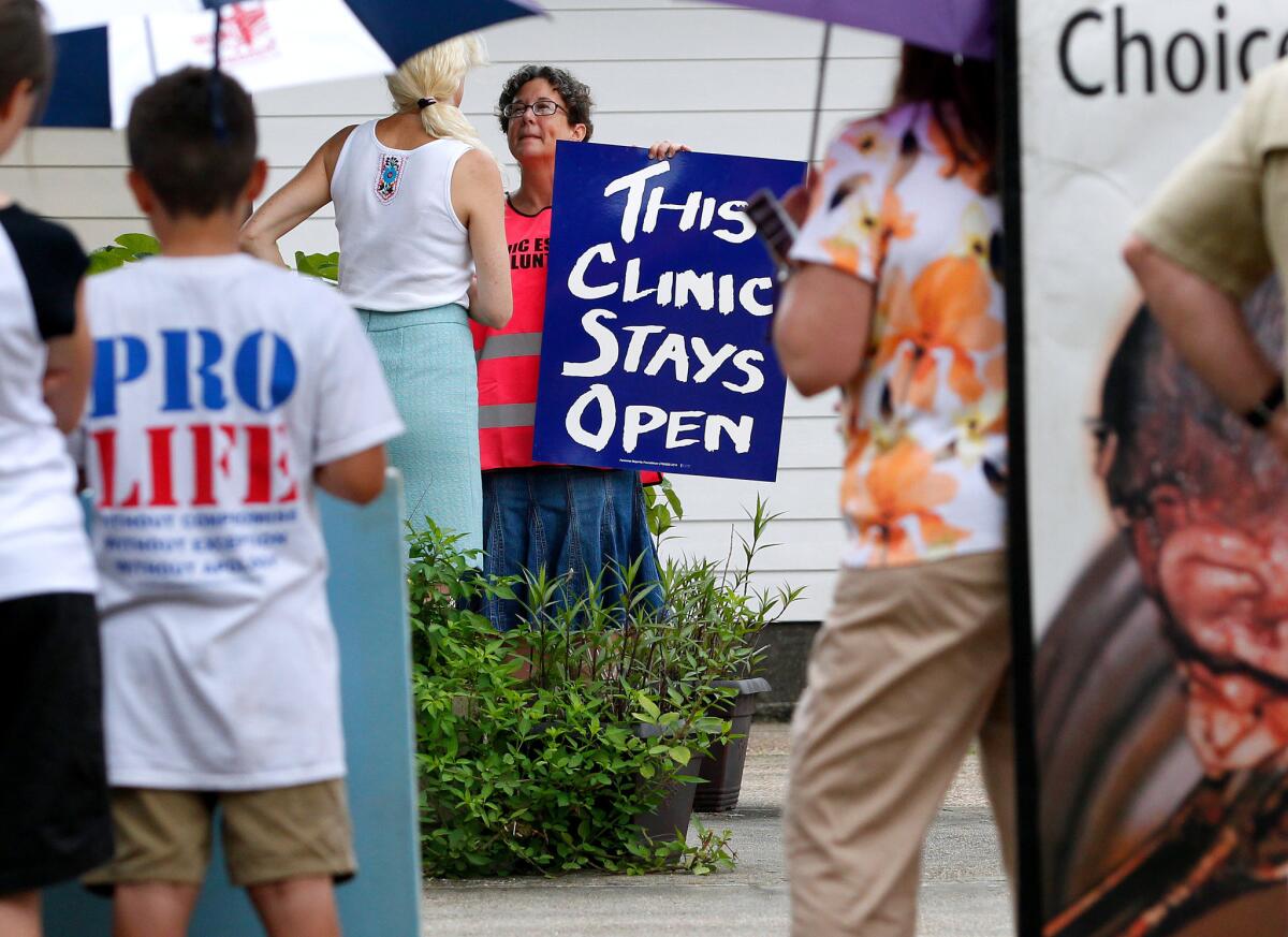 A volunteer guards the entrance to a clinic in Metairie, La., as antiabortion activists protest in 2014.