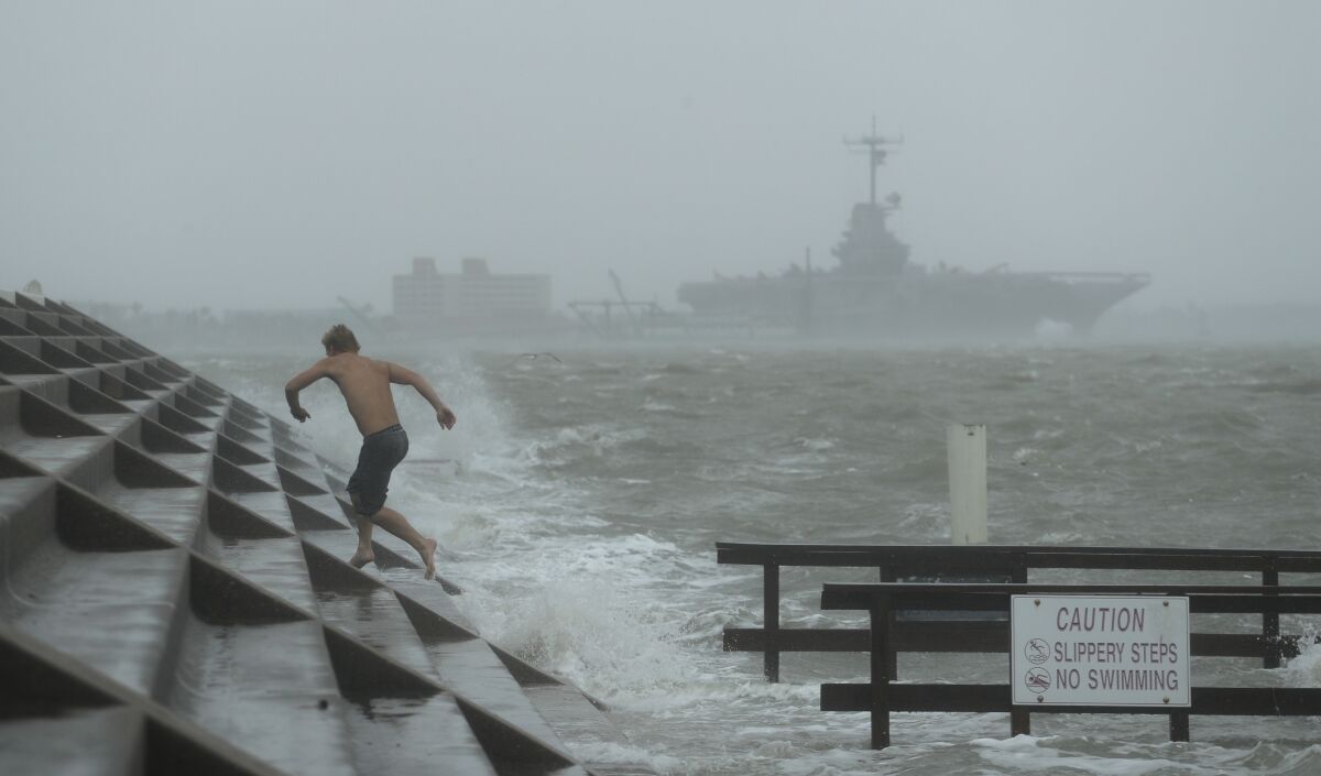 A beachgoer jumps to higher ground as Hurricane Hanna begins to make landfall Saturday in Corpus Christi, Texas.