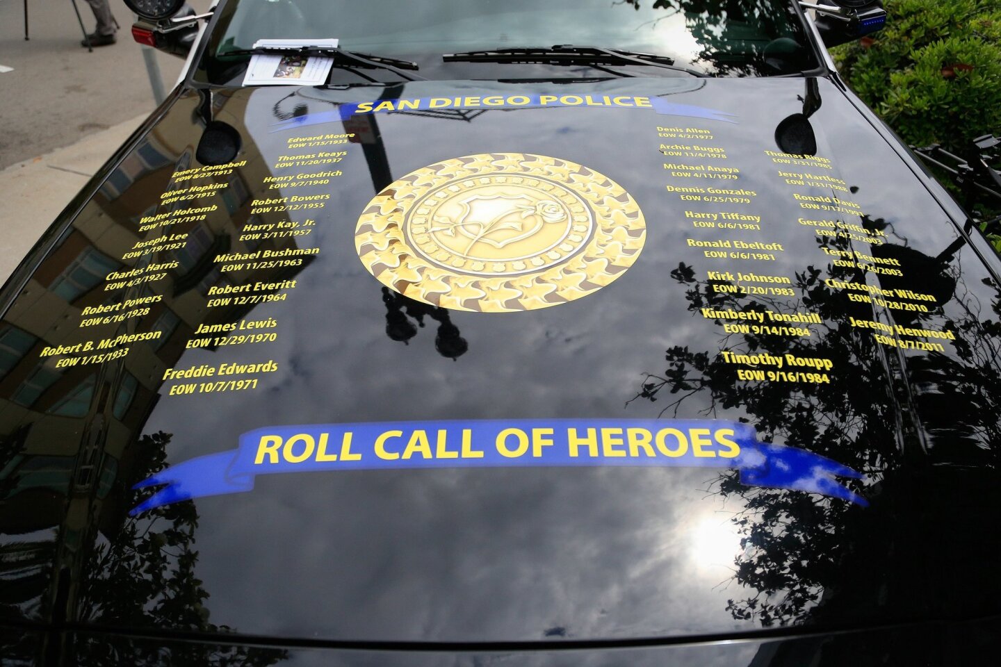 Photo of the hood of police car with "Roll Call of Heroes" list of names