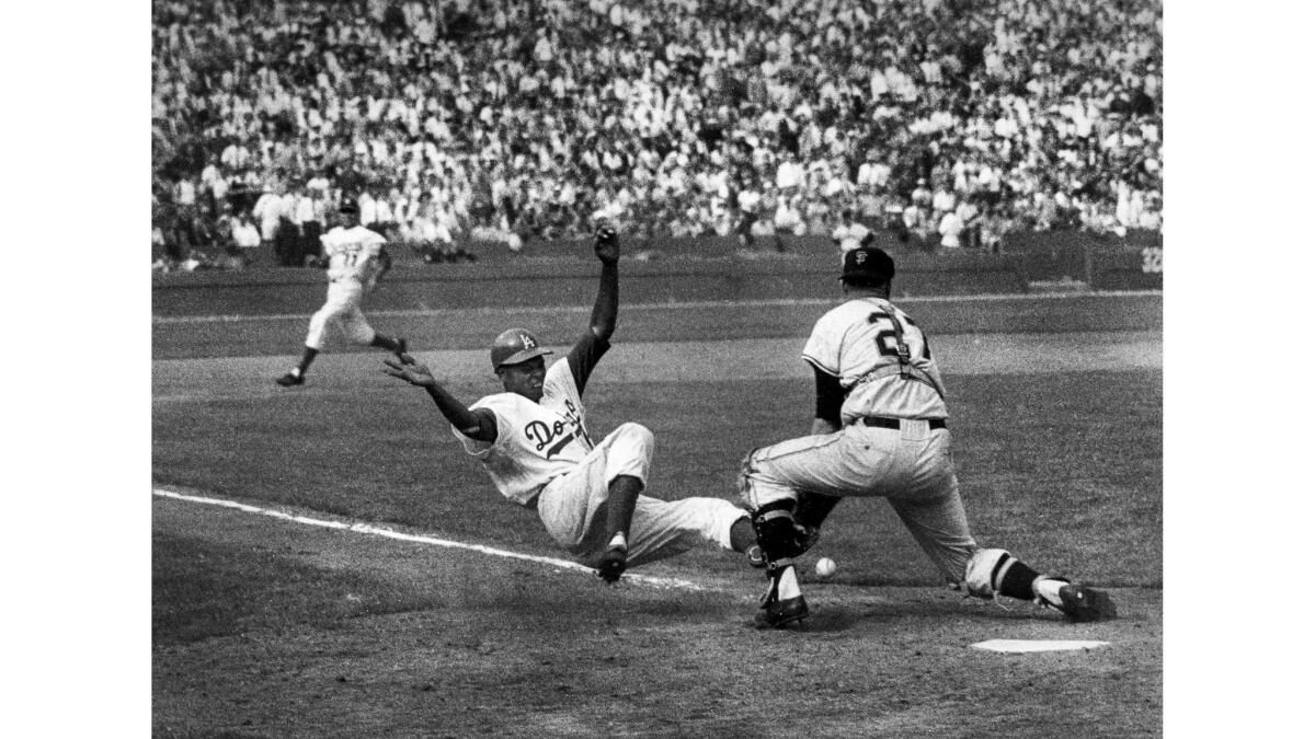 April 18, 1958: The Dodgers' Charlie Neal slides into Giants catcher Bob Schmidt, knocking the ball loose to score. Dick Gray, background, heading into third, also scored on the play that started with Gino Cimoli's single to right.