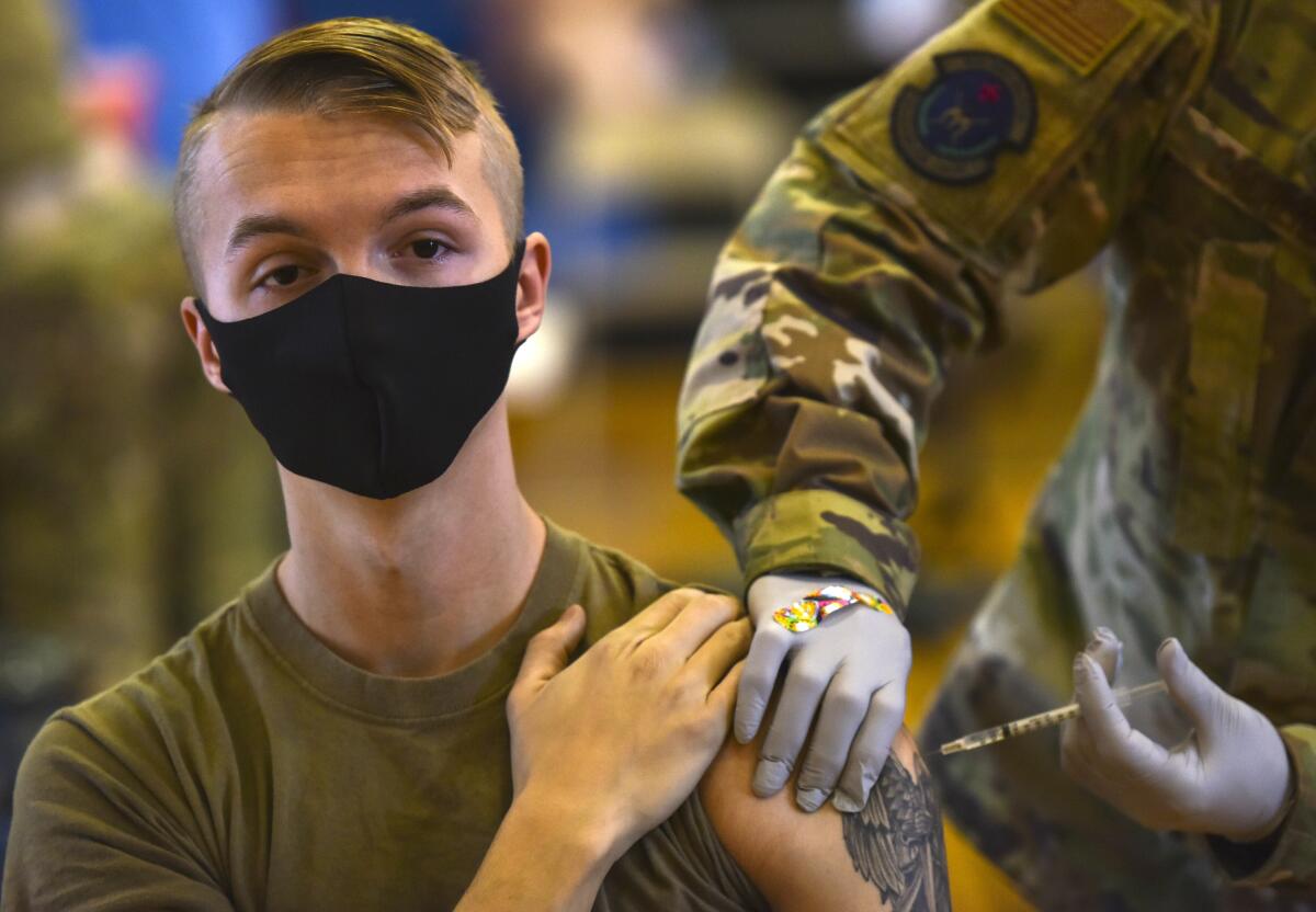 Militar con mascarilla recibe una vacuna contra el COVID-19