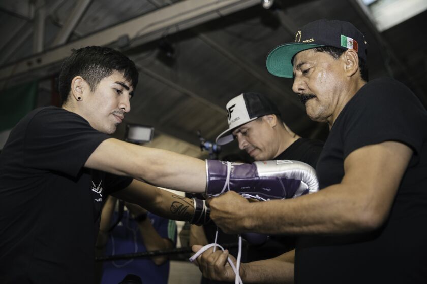 Jose Santa Cruz helps son Leo get ready for a recent media day training session. Jose will be in the corner when Leo fights Miguel Flores for the vacant WBA junior lightweight title Saturday in Las Vegas.
