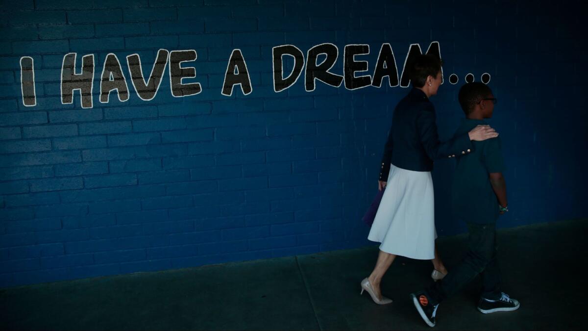 Jane Chu, chairwoman of the National Endowment for the Arts, is escorted by fourth-grader Jamiah Walker, 10, through the halls of Martin Luther King Jr. Elementary School in Compton.