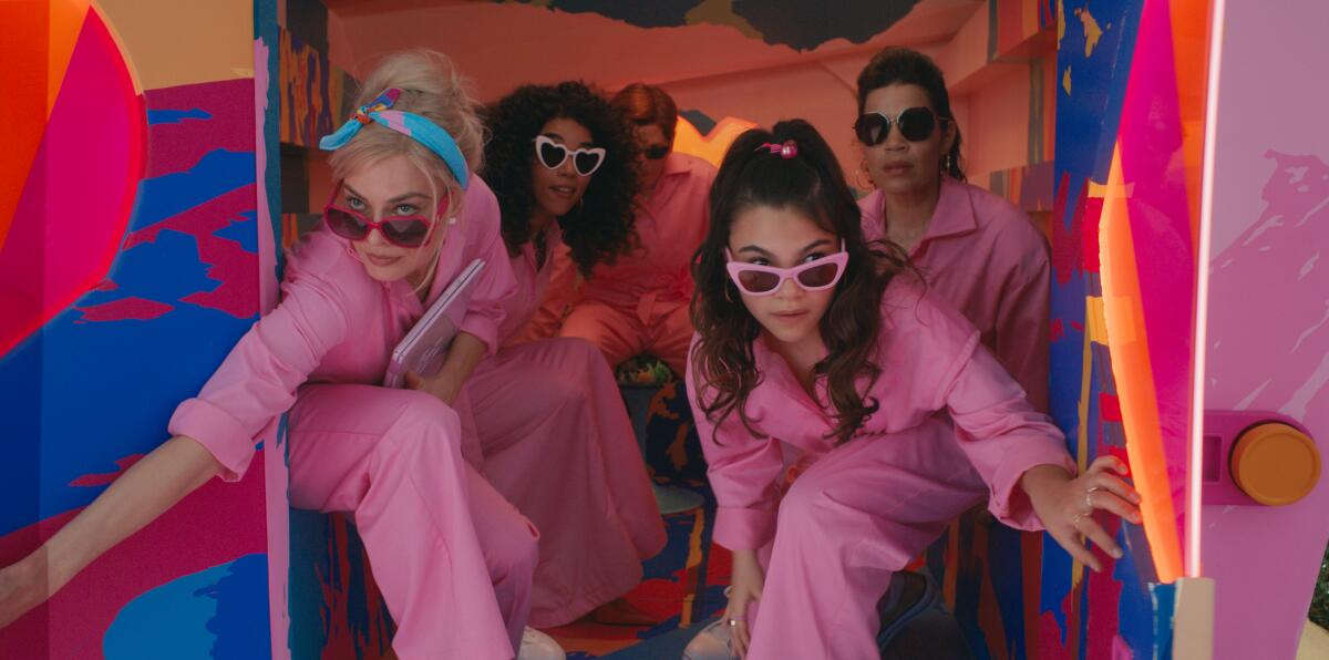 Four women in sunglasses and pink jumpsuits.