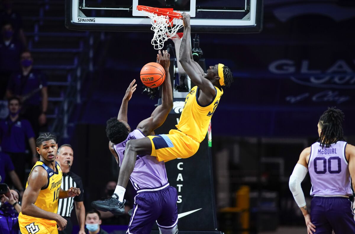Marquette forward Kur Kuath (35) finishes a dunk over Kansas State forward Kaosi Ezeagu (20) during the second half of an NCAA college basketball game Wednesday, Dec. 8, 2021,in Manhattan, Kan. At left is Marquette forward Justin Lewis and at right is Kansas State guard Mike McGuirl. Marquette won 64-63. (AP Photo/Nick Krug)