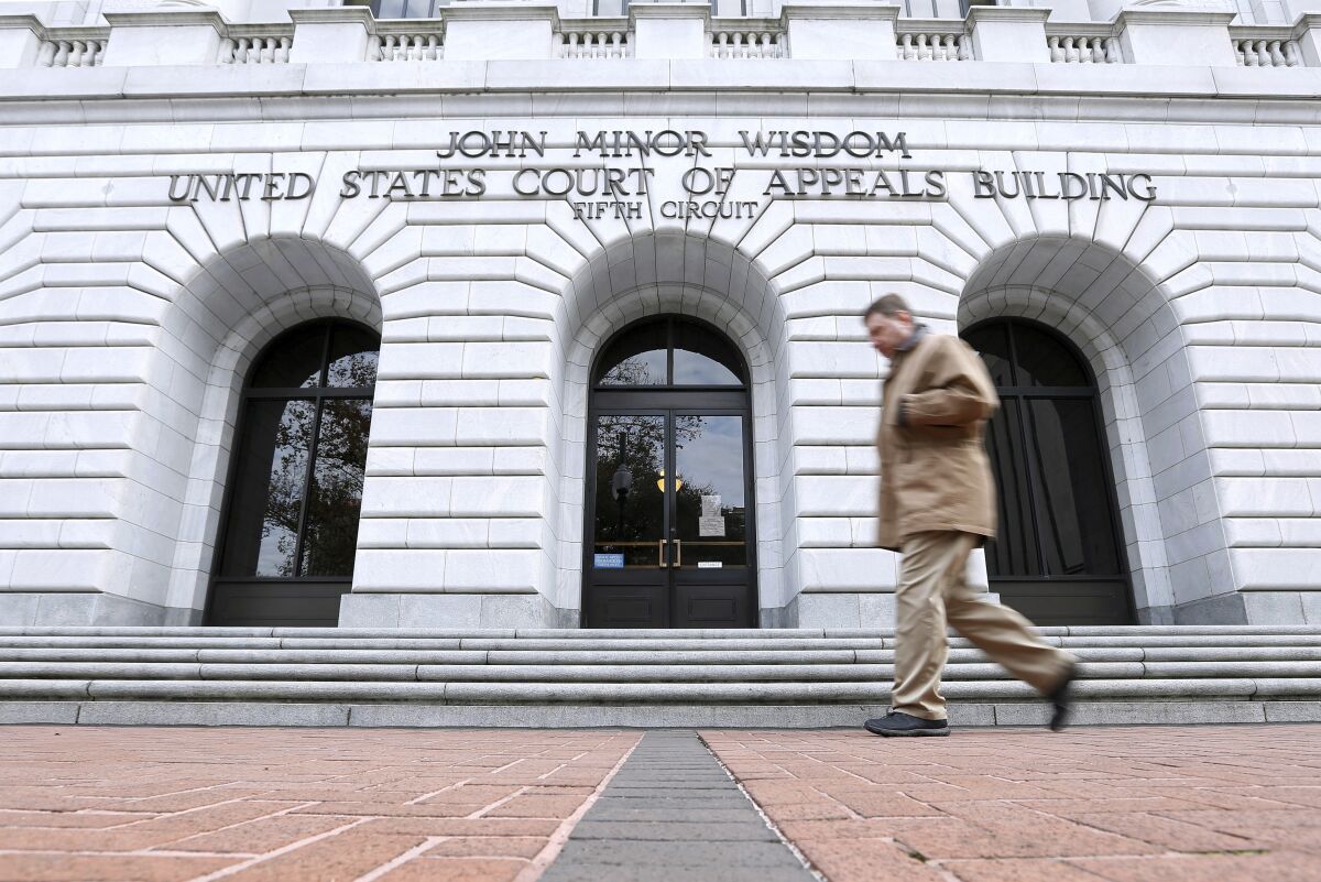 FILE - A man walks in front of the 5th U.S. Circuit Court of Appeals, Jan. 7, 2015, in New Orleans. A U.S. appeals court has declined for now to allow President Joe Biden's administration to require COVID-19 vaccinations for federal employees. The 5th U.S. Circuit Court of Appeals in New Orleans ruled 2-1 Wednesday, Feb. 9, 2022 to maintain a block on the mandate that a Texas-based federal judge issued on Jan. 21. (AP Photo/Jonathan Bachman, file)