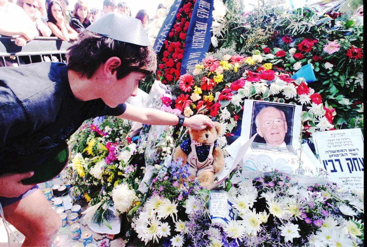 An Israeli schoolboy sets a teddybear on the grave of late Prime Minister Yitzhak Rabin at Mount Herzl Cemetery in Jerusalem Tuesday Nov. 7, 1995, a day after the funeral service.
