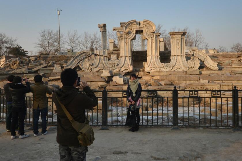 A woman (C) poses for photos at the ruins of the historic Jesuit designed Yuanying Guan (Immense Ocean Observatory) at the Old Summer Palace in Beijing on January 6, 2013. The Old Summer Palace, commissioned by the Chinese Emperor Qianlong and designed by Jesuit priests in a European style, was destroyed in 1860 by Anglo-French forces during the second Opium War. AFP PHOTO/Mark RALSTON (Photo credit should read MARK RALSTON/AFP/Getty Images)