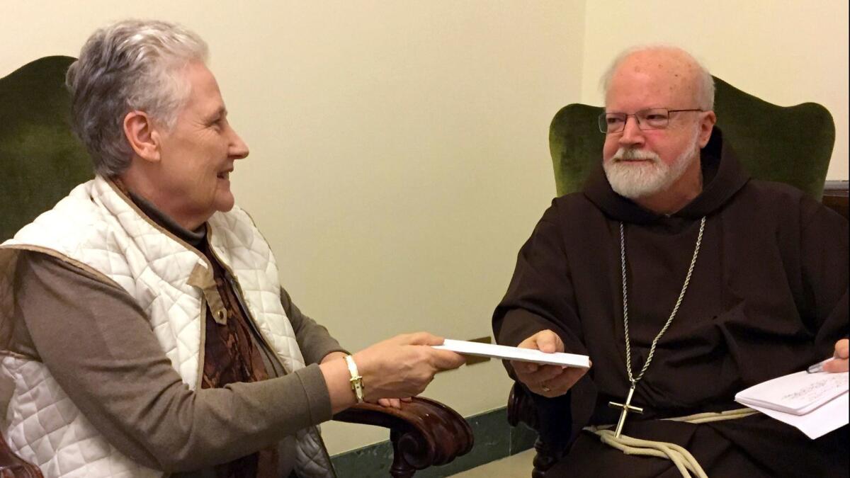 Marie Collins, then a member of the pope's sex abuse commission, in 2015 hands a letter to Cardinal Sean O'Malley detailing the abuse suffered by Juan Carlos Cruz of Chile.