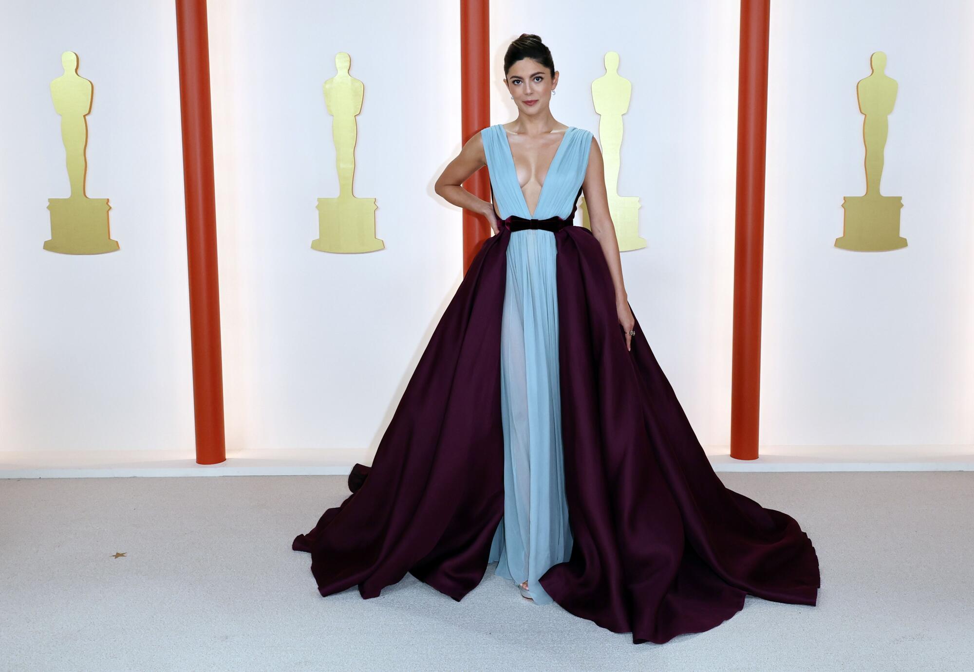 Monica Barbaro in a light blue gown with darker wrap-around, floor length skirt.