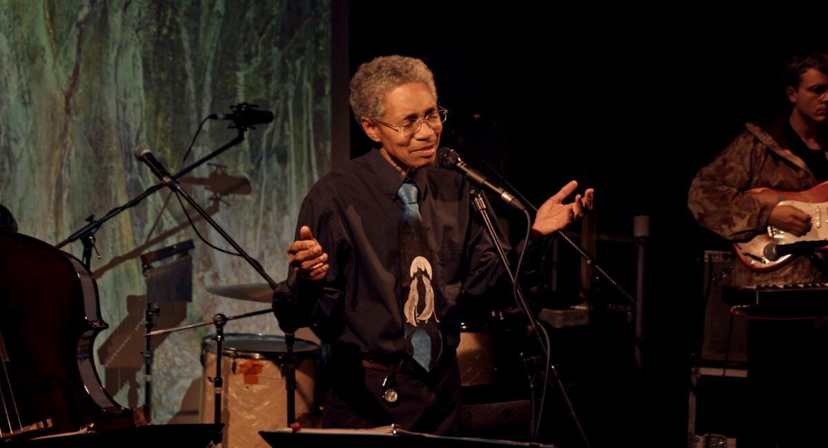 Beverly Glenn-Copeland at a microphone holds his hands out in the documentary "Keyboard Fantasies."