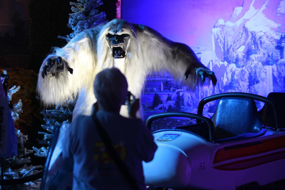 A woman takes photos of the Abominable Snowman and Matterhorn Bobsleds on display at a Disneyland history exhibit at the D23 Expo at the Anaheim Convention Center.