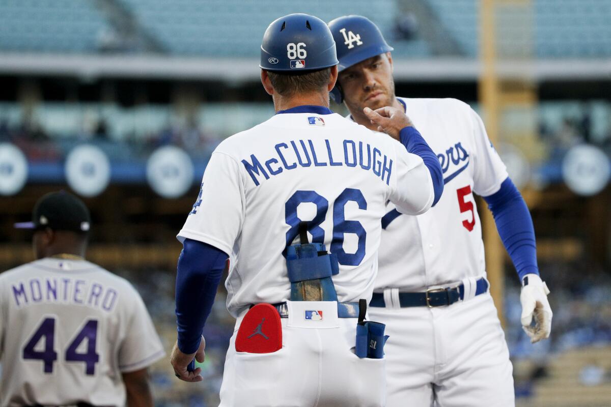 Dodgers' Freddie Freeman celebrates with first-base coach Clayton McCullough after hitting a single.
