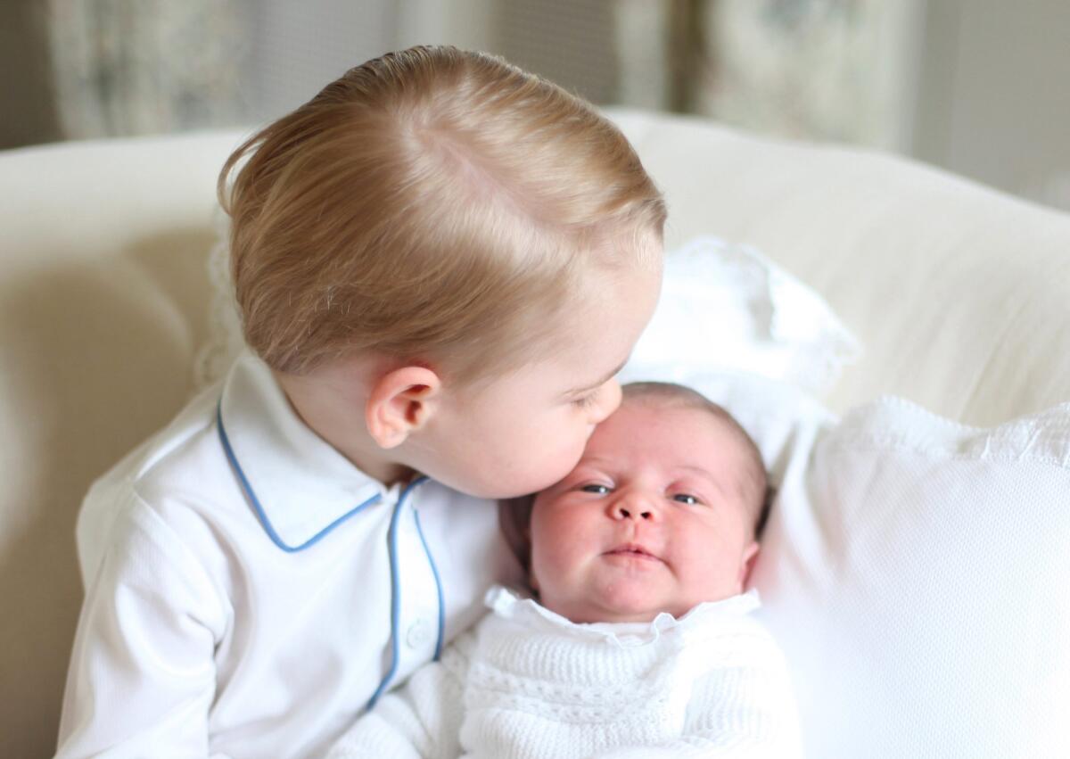 Prince George gives his sister Princess Charlotte a kiss in one of the first photos released of the royal siblings.
