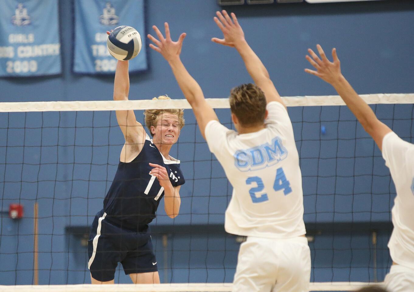 Newport Harbor's Jack Higgs (11) puts a kill past Corona Del Mar blockers Shane Premer (24) Glen Linden (11) during second round of the Battle of the Bay boys' volleyball match in Surf League play on Wednesday.