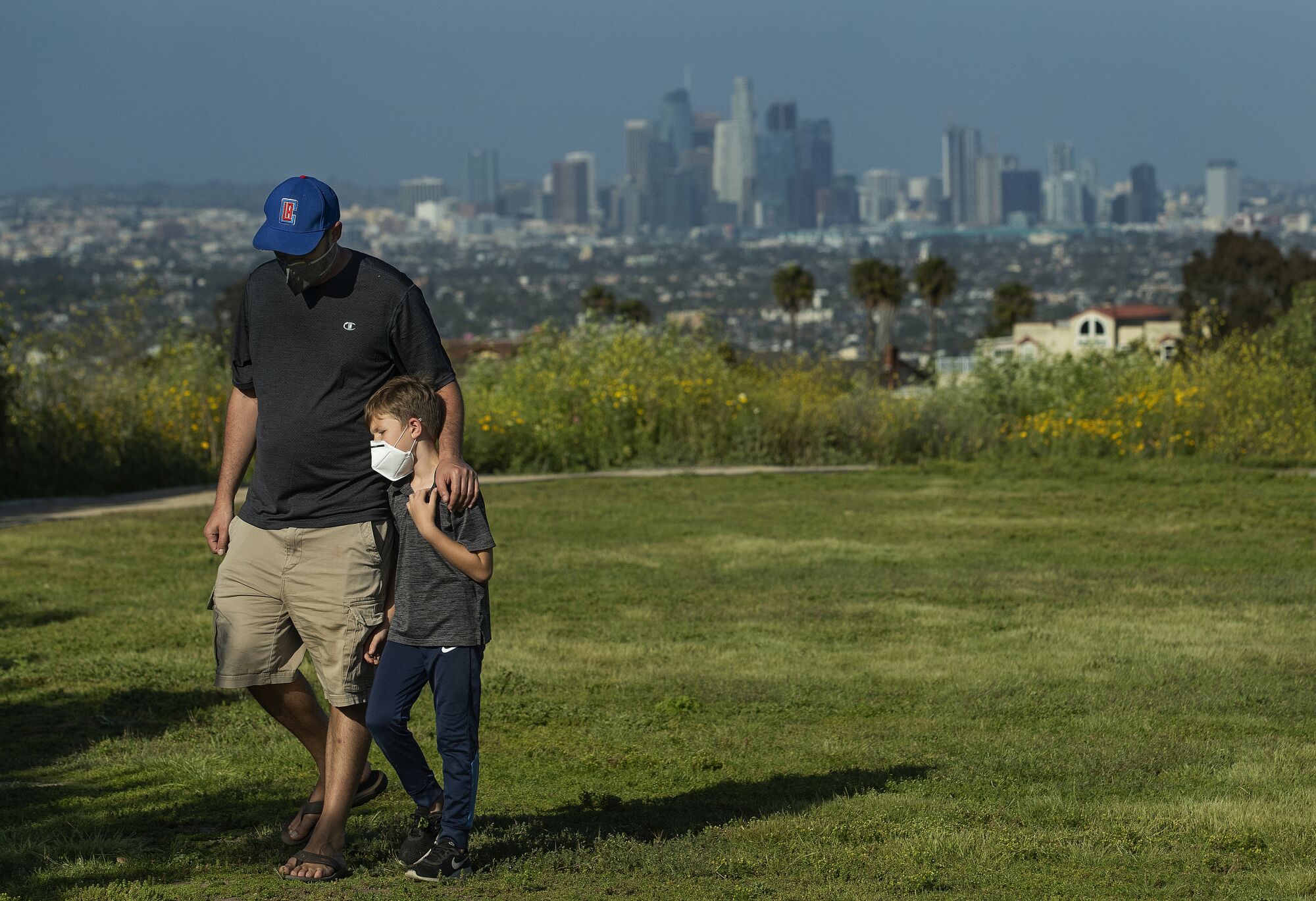 Lee Bloom, 39, of Los Angeles and his son Evan, 7 wear protective masks against the coronavirus during a visit to Kenneth Hahn State Recreation Area in Los Angeles.