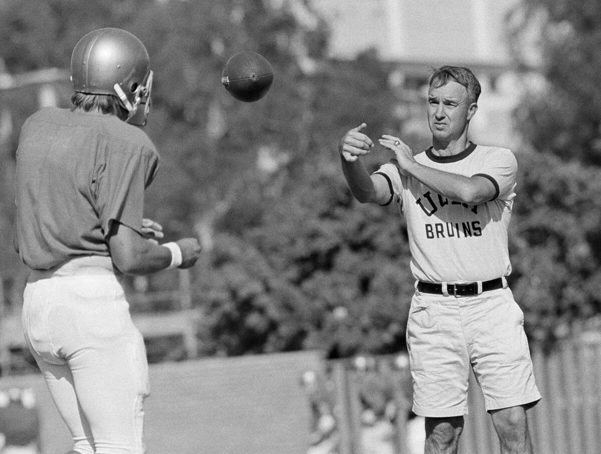 UCLA football coach Pepper Rodgers, right, tosses a ball to quarterback Mark Harmon during a team practice session on Sept. 13, 1972.