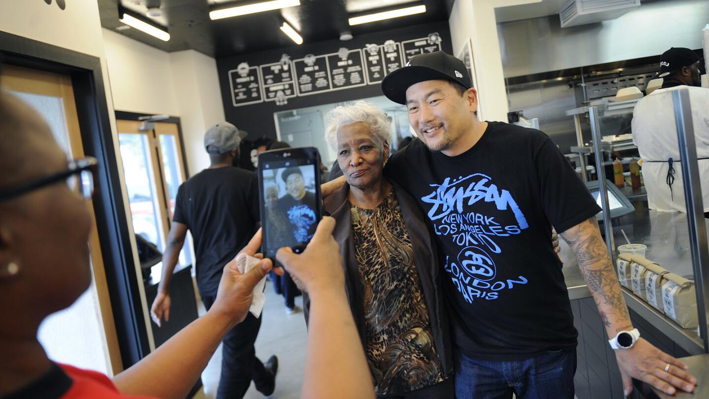 Tabitha O'Neal, left, takes a photo of her mother Delores, center, with Chef Roy Choi before dining at LocoL in Watts.