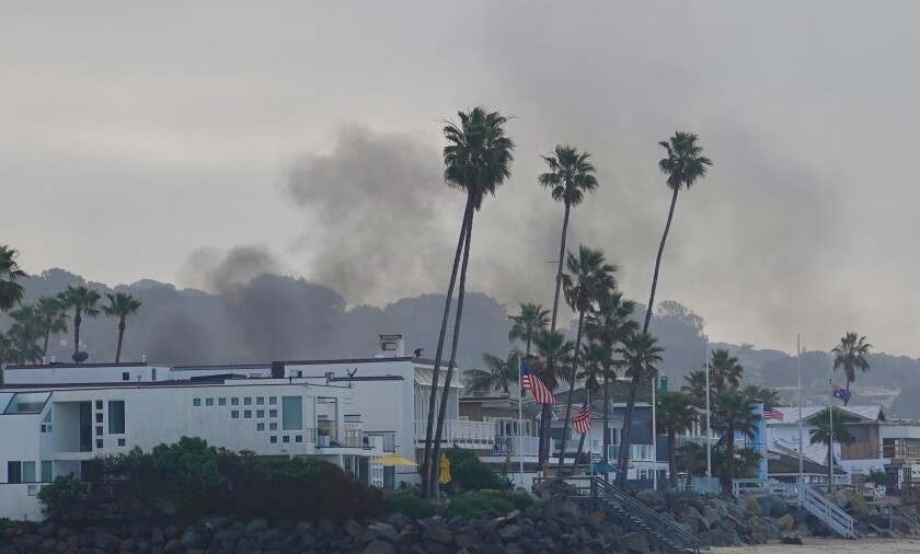 Smoke rises from a home fire on 25th Street in Del Mar on Sunday morning.