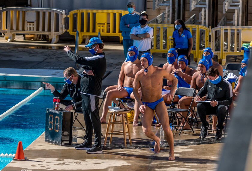 UCLA water polo coach Adam Wright, left, in hat, directs his players during a match.