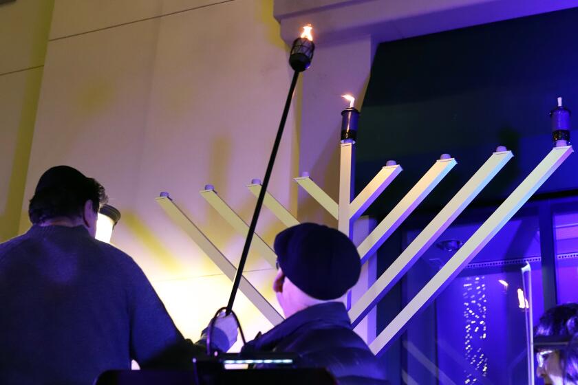 Asher Avital, of Newport Beach, lights the menorah for the start of Chanukah during Festival of Lights public Menorah lighting ceremony hosted by Chabad Center for Jewish Life at the Atrium Garden Court at Fashion Island in Newport Beach on Thursday, December 7, 2023. (Photo by James Carbone)