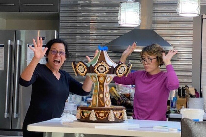Evonne Darby, left, and Sachiko Windbiel celebrate finishing assembly of the award-winning gingerbread carousel base.