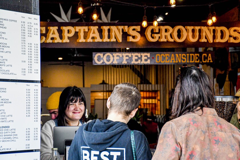 Three people standing under a sign that reads "Captain's Grounds."